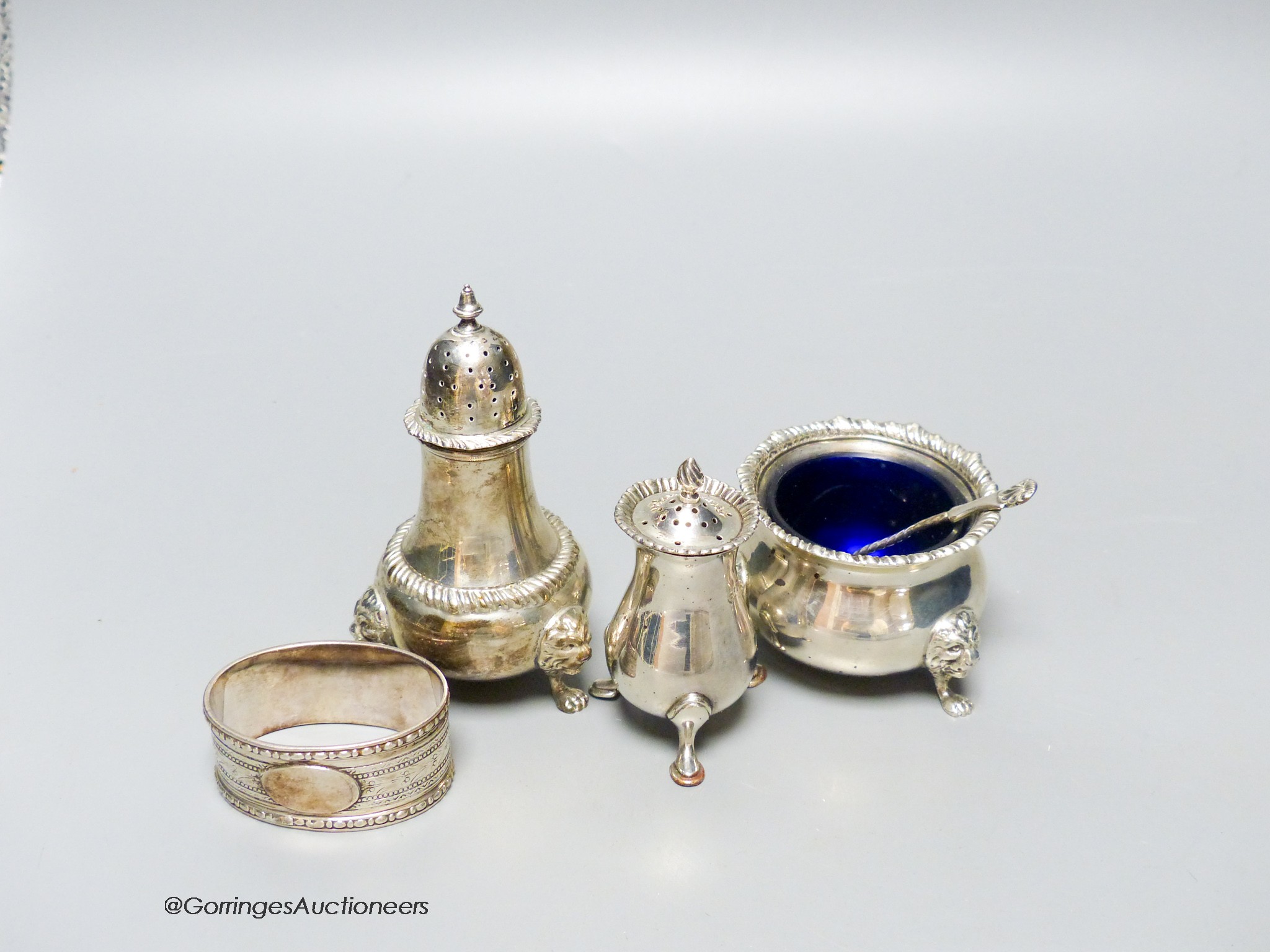 Two silver condiments by Harrods, one similar silver condiment, a silver spoon and a plated napkin ring.